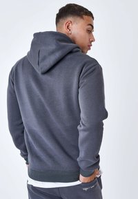 Sudadera gris con un acabado texturizado, que presenta una gran capucha, puños acanalados y una cintura ajustada. Diseñada con un corte casual.