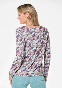 Langarmshirt mit einem bunten Blumenmuster und lila sowie türkisfarbenen Akzenten. Aus weichem, leichtem Stoff mit entspanntem Schnitt.