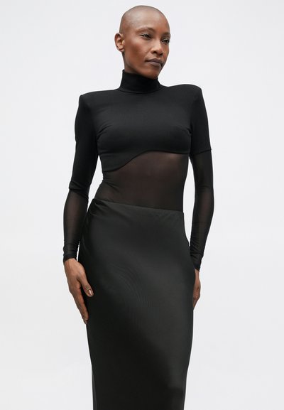 Rochie neagră cu un top ajustat, dotat cu un panou transparent și guler înalt, asociată cu o fustă lungă, netedă, dintr-o textură mata.