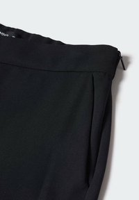 Sort stofpose med glat tekstur, lynlåslukning øverst og et foldet design, der viser rene linjer og ingen synlige mønstre.