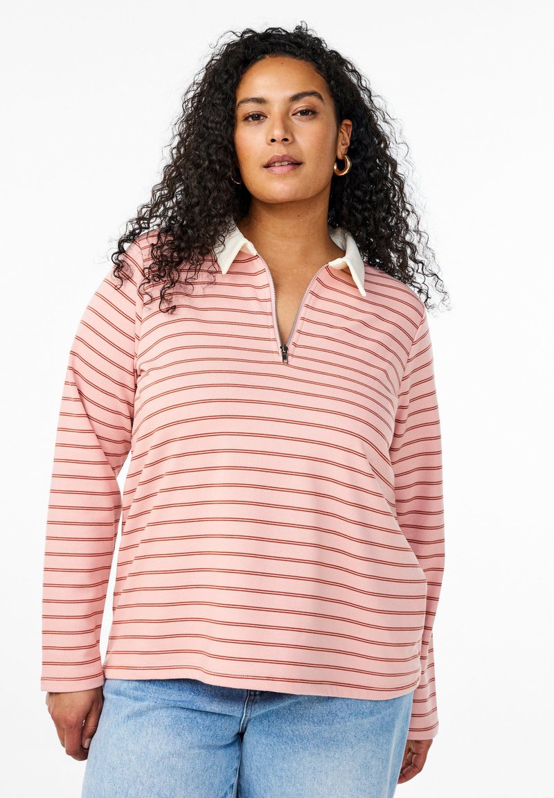 Maglia a maniche lunghe rosa chiaro con righe orizzontali rosse, chiusura frontale a mezza zip e colletto bianco a contrasto. Tessuto morbido, vestibilità comoda.