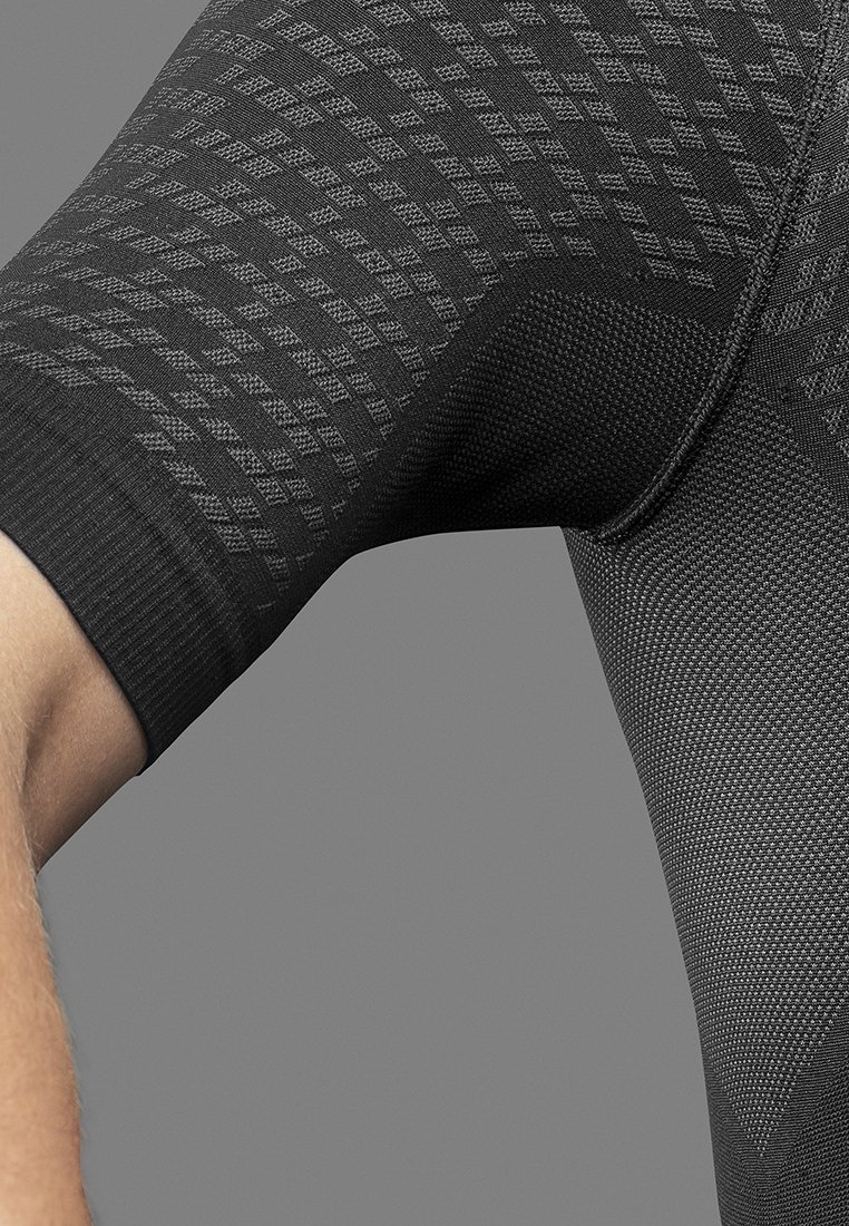 Nahaufnahme eines gebogenen Arms einer Person, die ein schwarzes, strukturiertes Kurzarm-Kompressionsshirt mit geometrischen Mustern trägt.