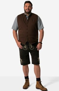 Brun knäppt väst över en blå rutig skjorta, svarta shorts med utsmyckad broderi, bruna stövlar och marinblå strumpor. Enkel, traditionell design.