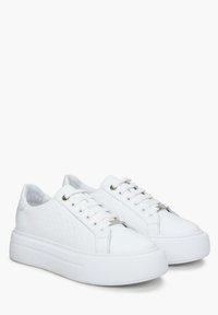 Witte sneakers met een gestructureerde synthetische bovenkant met cirkelpatroon, ronde neus, platte veters en een dikke rubberen zool. Geaccentueerd met zilverkleurige hardware.