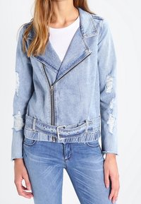 Světlemodrá džínová bunda s límečkem, zapínáním na zip, s worn efekty a páskem v pase. Vytvořeno v kombinaci s odpovídajícími džínovými kalhotami.
