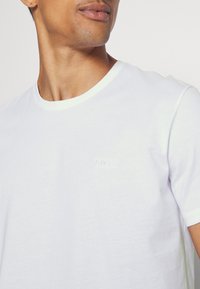 White cotton T-shirt with crew neck, short sleeves, featuring subtle "BOSS" logo in tone-on-tone embroidery on the chest.