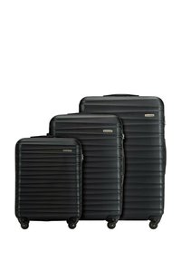 Tre valigie rigide nere, di diverse dimensioni, presentano un design rigato e una superficie liscia, con ruote multidirezionali per una facile manovrabilità.
