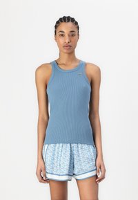 Blue ribbed tank top with a round neckline and a small green logo, paired with patterned light blue shorts featuring geometric designs.