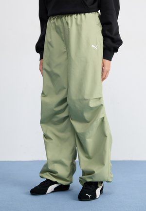 Puma loose-fit, lightweight pants in light green with an elastic waistband and side pockets; features a small white logo on the left thigh.