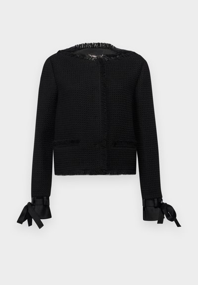 Jachetă neagră texturată cu guler și manșete cu franjuri. Are fundițe la capetele mânecilor și două buzunare frontale. Design de lungime medie.