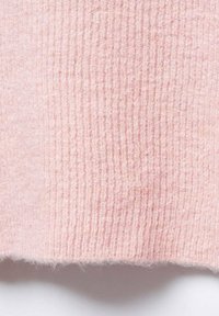 Tissu tricoté rose clair avec une texture côtelée, finition douce et pelucheuse, présentant des variations subtiles d'intensité de couleur.