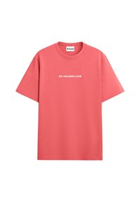 Coral short-sleeve t-shirt made of cotton with a crew neckline. Features white text reading "ON VACATION CLUB" across the chest.