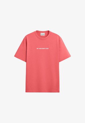 Coral short-sleeve t-shirt made of cotton with a crew neckline. Features white text reading "ON VACATION CLUB" across the chest.