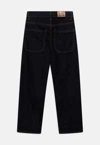 Jeans de mezclilla oscura con un diseño de pierna recta, costuras en contraste de color naranja y dos bolsillos traseros. Presenta una etiqueta de marca de cuero en la cintura.