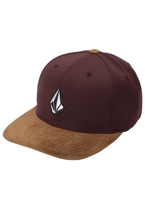 Baseballpet met een bruine suède klep en een donker bordeauxrode kroon met een zwart-wit geometrisch logo op het voorpaneel.