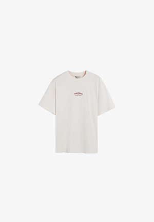 Tricou crem cu mânecă scurtă, fabricat din bumbac. Prezintă un mic logo roșu pe piept, croială lejeră și decolteu rotund.