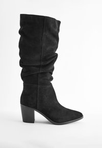 Botte haute jusqu'au genou en daim noir avec un design plissé, un bout carré et un talon épais. Texture lisse avec des détails de couture minimalistes.
