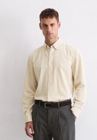 Lichtgele button-down overhemd met een slim fit en lange mouwen, gecombineerd met grijze maatwerkbroek en een donkere riem. Geweven stof zichtbaar.