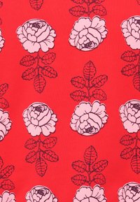 Tessuto rosso con un motivo floreale che presenta grandi rose rosa e foglie verdi, contornato in nero per il contrasto.