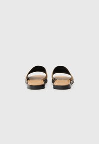 Sandales marron avec un matériau lisse en cuir synthétique, design ouvert au niveau des orteils et semelle en caoutchouc noir. Style simple et minimaliste sans accents supplémentaires.