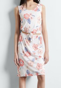 Sukienka w kwiaty wykonana z miękkiego materiału, z dekoltem w łódkę, zdobiona różowymi i granatowymi kwiatami, z paskiem do związania w talii, o długości do kolan.