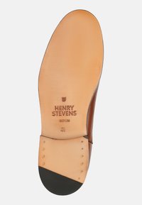 Semelle en cuir marron avec une surface beige lisse, texte de marque "HENRY STEVENS BERLIN" et taille "42", dotée d'un capuchon noir et de clous métalliques.