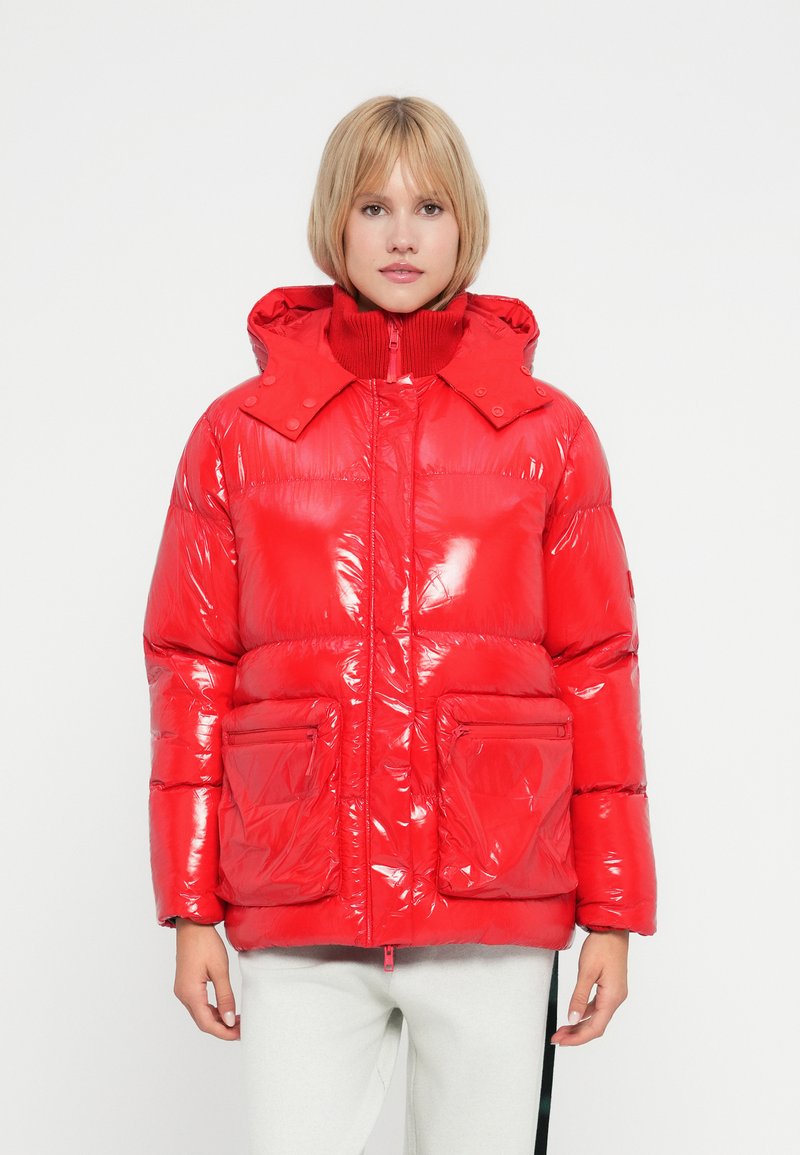 Doudoune rouge avec un extérieur brillant et matelassé, un col haut et une capuche. Équipée de poches avant et d'une fermeture éclair. Texture lisse.