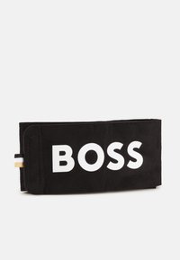 Čierna kožená peňaženka s výrazným bielym logom "BOSS", elegantným obdĺžnikovým dizajnom, textúrovaným povrchom a malým akcentovým pásikom na boku.