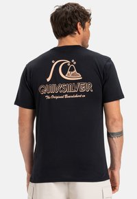 Černé bavlněné tričko s velkou grafikou broskve znázorňující vlnu a sopku, s textem "QUIKSILVER" pod ní v retro písmu. Krátké rukávy.