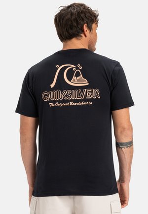 Schwarzes Baumwoll-T-Shirt mit einer großen Grafik eines Wellen- und Vulkanmotivs in Pfirsichfarbe, darunter der Text "QUIKSILVER" in einer retro Schriftart. Kurze Ärmel.