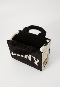 Petit sac fourre-tout rectangulaire avec une texture en polaire noir et blanc, des poignées doubles et un grand logo "DKNY" en lettres blanches sur le devant.