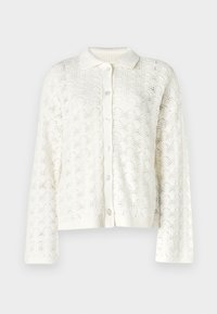 Bela pletena jopica z cvetličnim čipkastim vzorcem, z gumbom na zapiranju ter reberastim ovratnikom in manšetami. Ima dolge rokave in odprto pleteno teksturo.