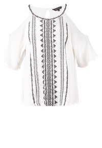 Vit blus med kallaxel-design, prydd med svart geometrisk broderi längs mitten och utsvängda ärmar. Nyckelhålsdetalj på ryggen.