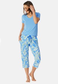 Lichtblauw korte mouwen V-hals top, gecombineerd met losse, korte broek met een groen en blauw bladerenpatroon en een trekkoord.