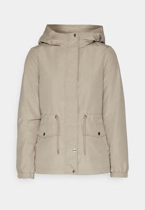 Beige bunda s kapucí na zip, se stahovacími šňůrkami v pase a dvěma předními kapsami. Má elastické manžety a hladký, voděodolný povrch.