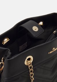 Sort faux læder håndtaske med guldfarvet hardware. Har kædehenkel, magnetlukning og chevron-syning. Indeni er der en lynlåslomme.