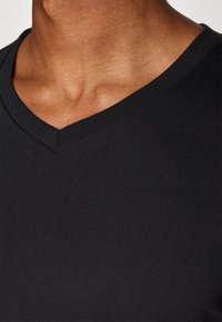 Black V-neck t-shirt with a soft cotton texture, featuring a clean finish and a fitted design around the neck and shoulders.