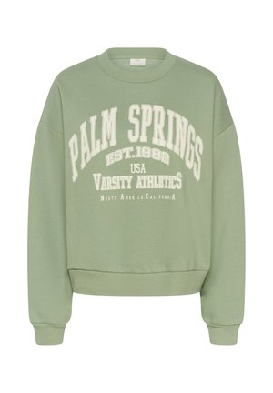 Sweatshirt vert avec des poignets et un ourlet côtelés. Présente un texte blanc : "PALM SPRINGS EST.1982 USA VARSITY ATHLETICS." Tissu doux, design cropped.