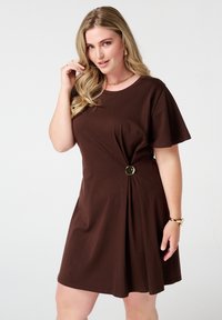 Robe en coton marron à manches courtes, décolleté rond et détail torsadé à la taille avec un accent rond en ton doré. Texture lisse.