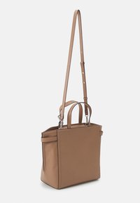 Sac fourre-tout synthétique marron avec de courtes poignées doubles et une longue bandoulière réglable, présentant une forme structurée et de subtils détails de couture.