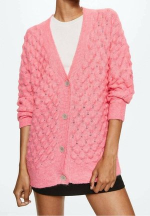 Roze gebreide cardigan met een gestructureerd bubblepatroon, v-hals en vijf lichtgrijze knopen. Beschikt over geribde manchetten en zoom.