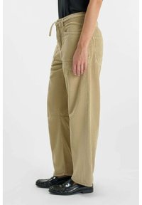 Beige corduroy broeken met een losse pasvorm, voorzien van een trekkoord in de taille en voordo pockets, gecombineerd met zwarte instappers. Geweven stof zichtbaar.