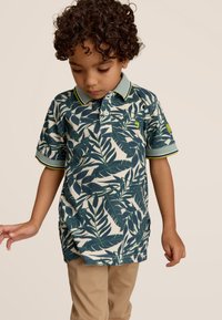 Korte mouwen polo shirt met een donkergroen bladerenpatroon op een lichte achtergrond, voorzien van een gestreepte kraag en subtiele branding op de mouw.