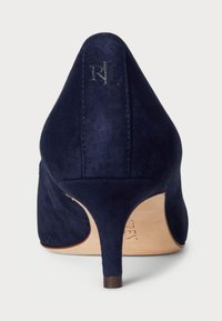 Ναυτικό μπλε σουέτ ψηλοτάκουνο παπούτσι με μυτερή μύτη και λεπτό τακούνι. Διαθέτει ένα διακριτικό λογότυπο ανάγλυφο στο πίσω μέρος. Λείος υφασμάτινος χαρακτήρας.