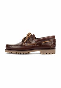 Zapato náutico de cuero marrón con una textura suave, costuras blancas y cordones en contraste en color tostado. Presenta una suela de goma con un patrón en forma de zigzag.