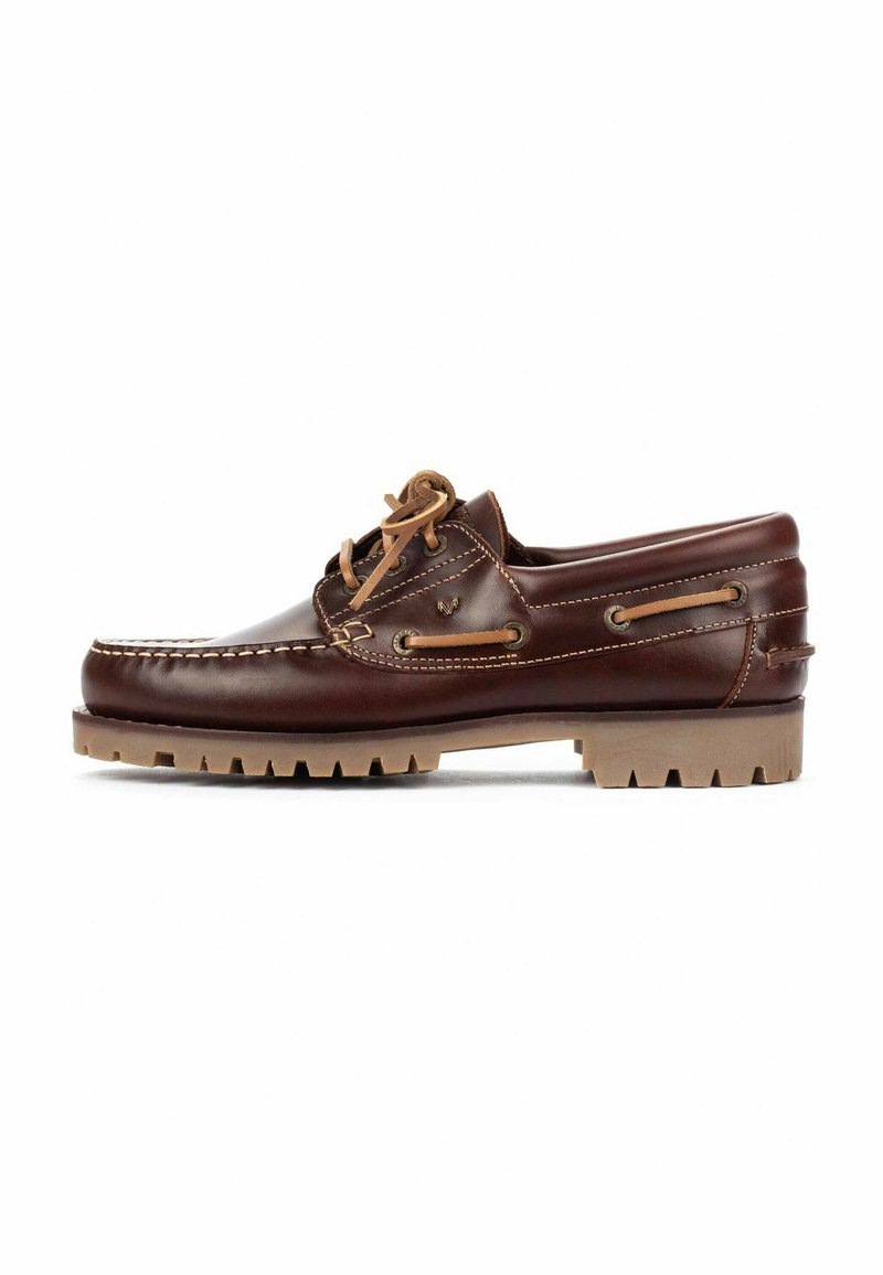 Zapato náutico de cuero marrón con una textura suave, costuras blancas y cordones en contraste en color tostado. Presenta una suela de goma con un patrón en forma de zigzag.