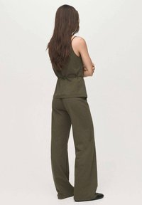 Olijfgroene mouwloze top en wijde broek van een zachte, textuurstof, met een relaxte pasvorm en minimale ontwerpdetails.