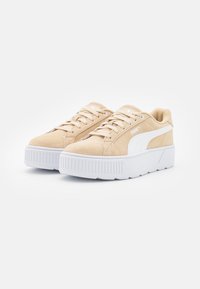 Sneaker in suede beige con dettagli bianchi, design con lacci, suola piattaforma con texture a righe e marchio sul lato.