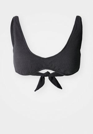 Musta bikinitoppi, joka on valmistettu teksturoidusta kankaasta. Siinä on leveä pyöreä kaula-aukko, paksut hihnat ja solmimislukko etuosassa.