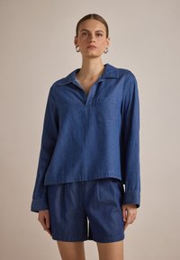 Sinine denim pikakätisega särk, millel on kraega kaelus ja eesmine tasku, lõdva istuvusega, koos sobivate lühikeste pükstega. Sujuv tekstuur, juhuslik disain.